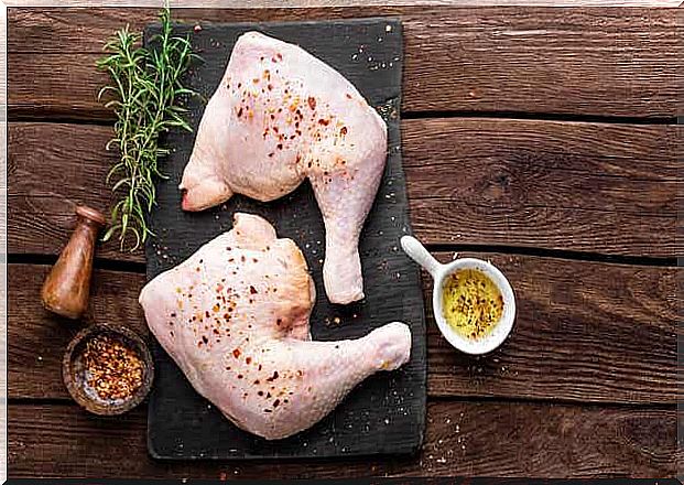 Cutting board with raw chicken and herbs