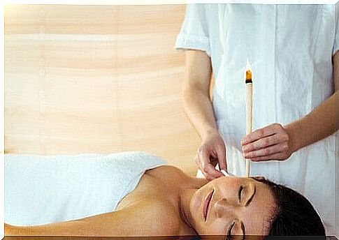 Woman lies on her back with an ear candle in her right ear