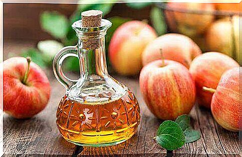 bottle of apple cider vinegar and loose apples