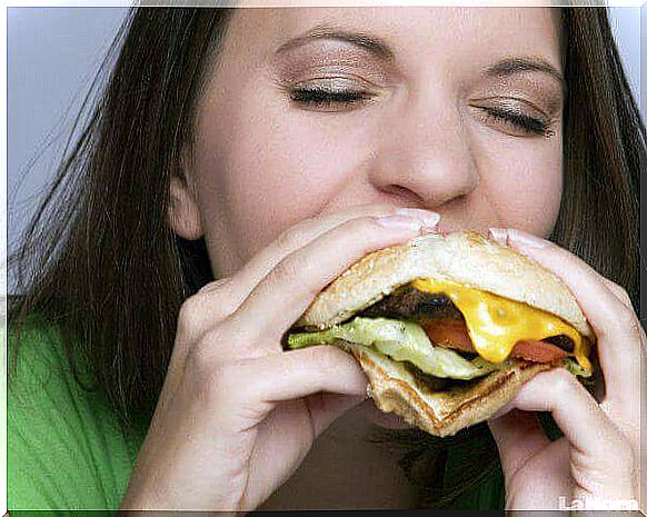 Woman eats a hamburger with her eyes closed