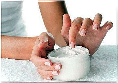 A woman taking some lotion from a jar